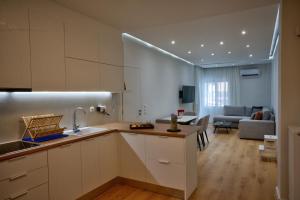 a kitchen with white cabinets and a living room at The Cosy luxurious Seaside Apartment in Athens