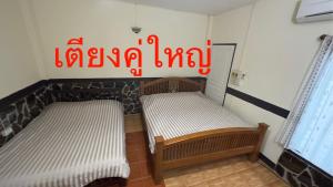 duas camas num quarto com uma placa na parede em ช่อฟ้า การ์เด้น em Phrae