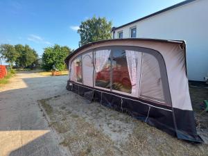 uma tenda sentada no chão ao lado de um edifício em Przyczepy Kempingowe OSK LOK by Q4Camp em Jastarnia