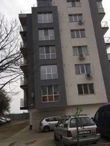 a tall building with cars parked in front of it at Уютен нов апартамент - Стара Загора с две спални in Stara Zagora