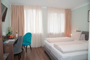 a bedroom with a bed and a desk and a window at Hotel & Restaurant Knote in Sindelfingen