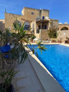 a swimming pool in front of a house at Botanica B&B in Xagħra