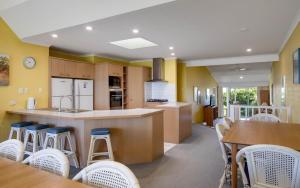 uma cozinha com paredes amarelas, mesas e cadeiras em Beachfront Great for the Family em Encounter Bay