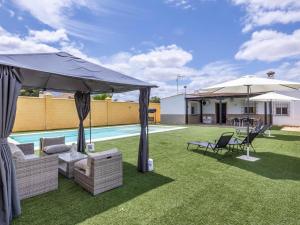 un patio avec chaises et parasols à côté d'une piscine dans l'établissement Villa Santa Teresa Vacacional Sevilla, à Dos Hermanas