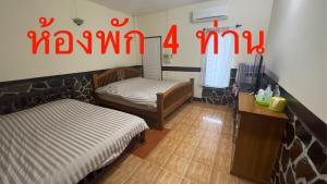 een kamer met 2 bedden en een tv. bij ช่อฟ้า การ์เด้น in Phrae