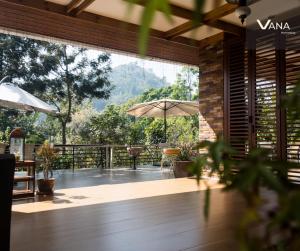 a patio with a table and an umbrella at VANA Homestay in Ban Tai