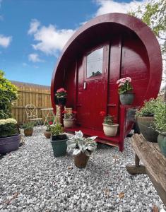 un cobertizo rojo con macetas en un patio en Alnmouth Glamping, en Alnmouth