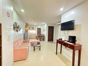 a living room with a couch and a desk with a television at Sebastien Hotel in Mactan