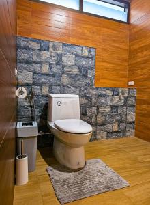 a bathroom with a toilet and a stone wall at Sanaepatan Home Resort - เสน่ห์ป่าตาล โฮม รีสอร์ต in Ban Buak Khang