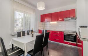 a kitchen with red cabinets and a white table and chairs at Stunning Home In Jadranovo With 4 Bedrooms, Wifi And Outdoor Swimming Pool in Jadranovo