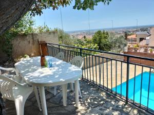 un tavolo bianco con sedie su un balcone con piscina di Casa Flor de Taronger a Viladecáns