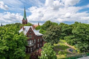 un gran edificio de ladrillo con un campanario sobre los árboles en Apartamenty Yeti & Wilka w Centrum Chorzowa: Wilk, en Chorzów