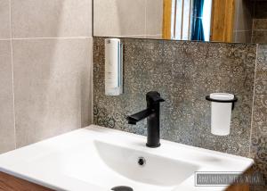 a bathroom sink with a black faucet on a wall at Apartamenty Yeti & Wilka w Centrum Chorzowa: Wilk in Chorzów +16 photos