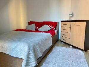 een slaapkamer met een rood bed en een dressoir bij Piękny apartament z widokiem na Jezioro Niegocin in Giżycko