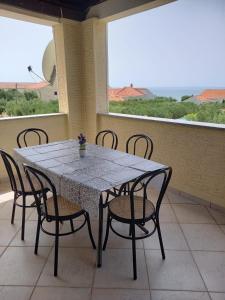 een tafel en stoelen op een balkon met uitzicht op de oceaan bij Apartman Privlaka in Privlaka