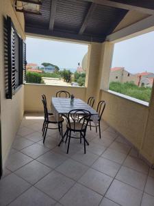 een tafel en stoelen op een balkon met een tafel en ramen bij Apartman Privlaka in Privlaka