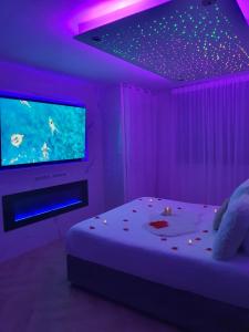 una camera con letto e TV con luci viola di The Love Room Marseille a Plan-de-Cuques