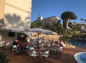 een groep mensen die aan tafels bij een zwembad zitten bij El Dorado 114 luxury with full air-conditioning in Playa de las Americas