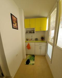 een keuken met gele kasten en een vloermat bij Danaya's apartment in Varna