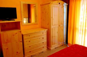 1 dormitorio con TV y tocador con cómoda en Hotel Miramonti, en Gambarie dʼAspromonte