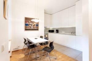 a kitchen with white cabinets and a white table and chairs at Saint John 2 Bedroom Cottage by Reside Baltic in Vilnius