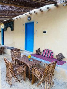 un patio con mesa y sillas y una puerta azul en خزفستا Khazfista, en ‘Izbat an Nāmūs