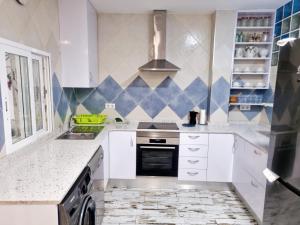 een keuken met witte apparatuur en blauwe en witte tegels bij PLANTA BAJA-BENICARLO in Benicarló