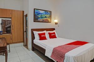 Un dormitorio con una cama con almohadas rojas. en OYO 92638 Jr Residence Syariah, en Medan