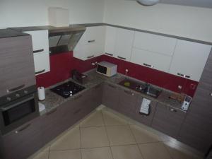 a kitchen with white cabinets and a red wall at Villa Halcyon cabo verde in Cidade Velha
