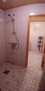 baño con ducha y suelo de baldosa. en Kissankello, en Ruokola