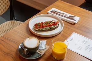 a table with a sandwich and a cup of coffee and orange juice at Hotel Indigo Belgrade, an IHG Hotel in Belgrade