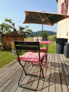 een tafel en stoel met een paraplu op een terras bij Gite romantique de la Ferme du Pral in Saint-Victor