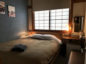 a bedroom with a bed and a desk and a window at DJANGO Hostel & Lounge in Tanabe