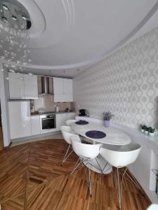 a kitchen with a table and some white chairs at Apartament Lawendowy in Jastrzębia Góra