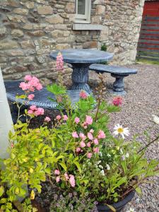 eine Steinbank in einem Garten mit Blumen in der Unterkunft The Old House at Belfield in Tralee