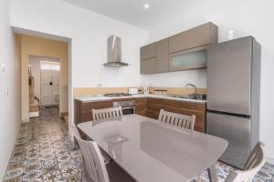 a kitchen with a white table and white chairs at Town House Luqa in Luqa