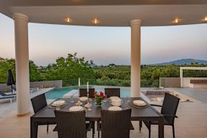 comedor con mesa, sillas y piscina en Villa Moonstone, en Mouzákion