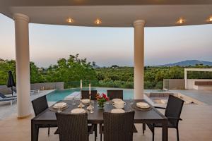 a dining room with a table and chairs and a pool at Villa Moonstone in Mouzákion