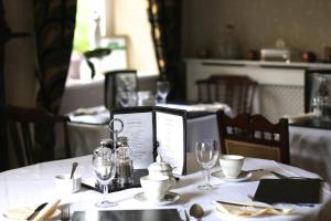 a table with a white table cloth with wine glasses at Afon Rhaiadr Country House in Dolgellau