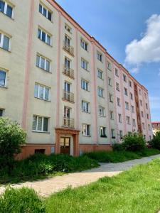 un grand bâtiment rose avec une pelouse devant lui dans l'établissement Apartmán Šnyt Primka, à Olomouc