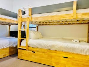 two bunk beds in a dorm room with white sheets at Snowcreek 2 Alpine Chalet, Private Garage in Thredbo