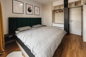 a bedroom with a large bed with a green headboard at Apartment FRIENDs Bratislava in Bratislava