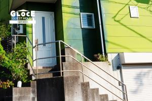 un edificio con escaleras que conducen a una puerta azul en GLOCE葉山サンセットハウスMORITO l バルコニーから葉山の海と町を一望 小型犬玄関と庭のみアクセス可 en Hayama
