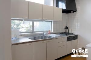 a kitchen with white cabinets and a sink and a window at GLOCE葉山サンセットハウスMORITO l バルコニーから葉山の海と町を一望 小型犬玄関と庭のみアクセス可 in Hayama