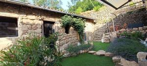 a stone house with a yard with green grass at Le Temps Suspendu in Saint-Pierreville