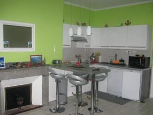 a kitchen with green walls and a fireplace with bar stools at Chez Ghys in Eaux-Bonnes