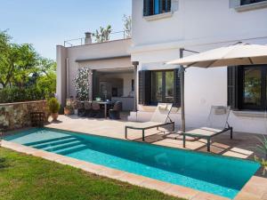 a swimming pool with two chairs and an umbrella next to a house at Chalet sea and mountain views - 5 min from Golf in Sant Vicenç de Montalt