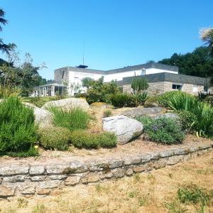un jardin avec des rochers et des plantes devant un bâtiment dans l'établissement Domaine de la Chesnaie, à Josselin