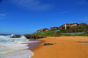 a beach with houses on a cliff and the ocean at 15 Dorado Bay in Tinley Manor