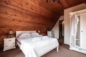 ザコパネにあるWilla Apartの白いベッドと木製の壁が備わるベッドルーム1室が備わります。